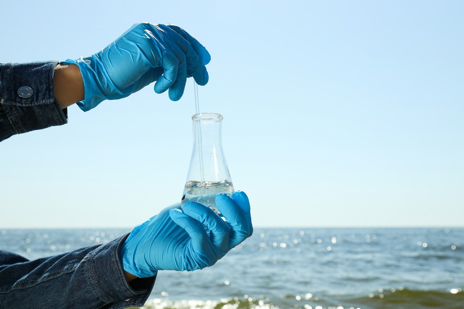 A test tube with river water in hands in blue gloves