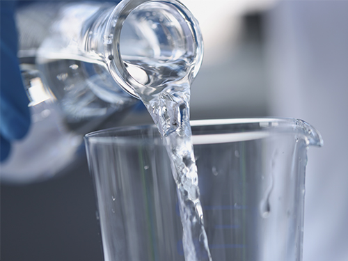 closeup of water sample being poured into beaker.