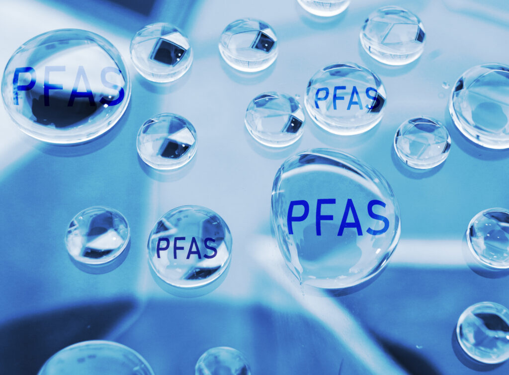 Closeup of waer droplets with the word "PFAS" written in each.