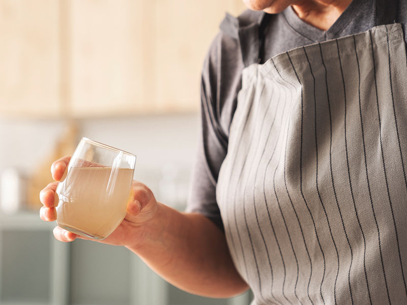 Woman holding glass of cloudy tap water.